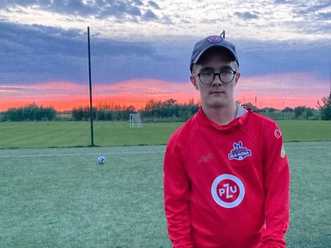 Sebastian na boisku piłkarskim o zachodzie słońca
